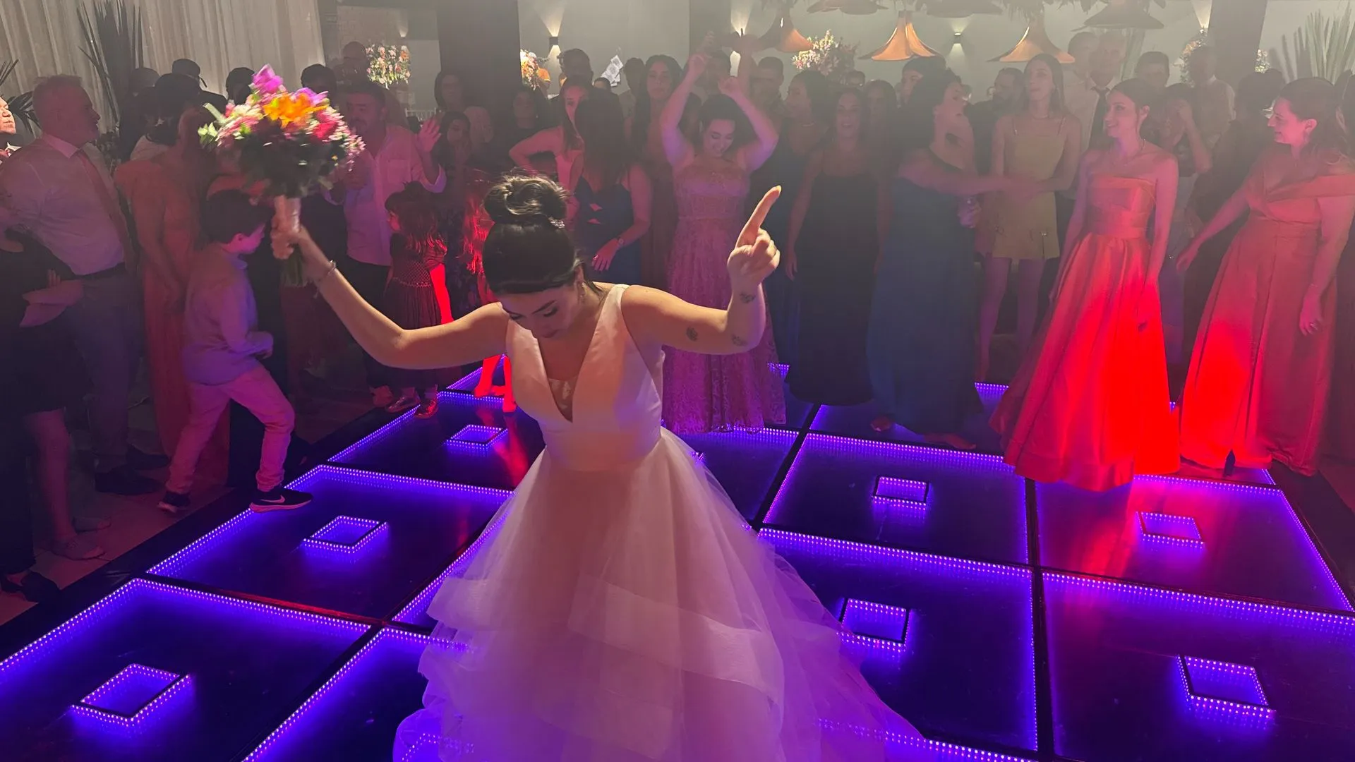 Uma noiva está segurando um buquê de flores enquanto dança na pista de dança.