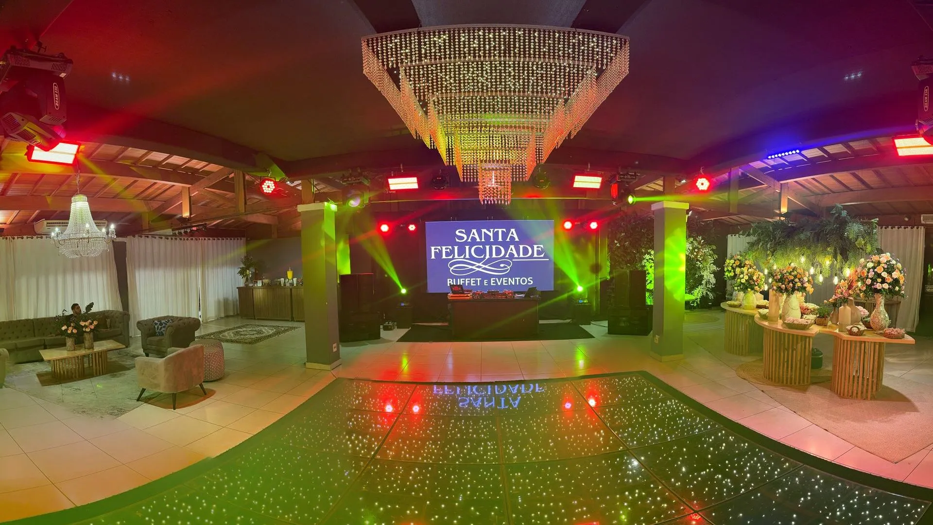 Uma grande sala com pista de dança e lustre.