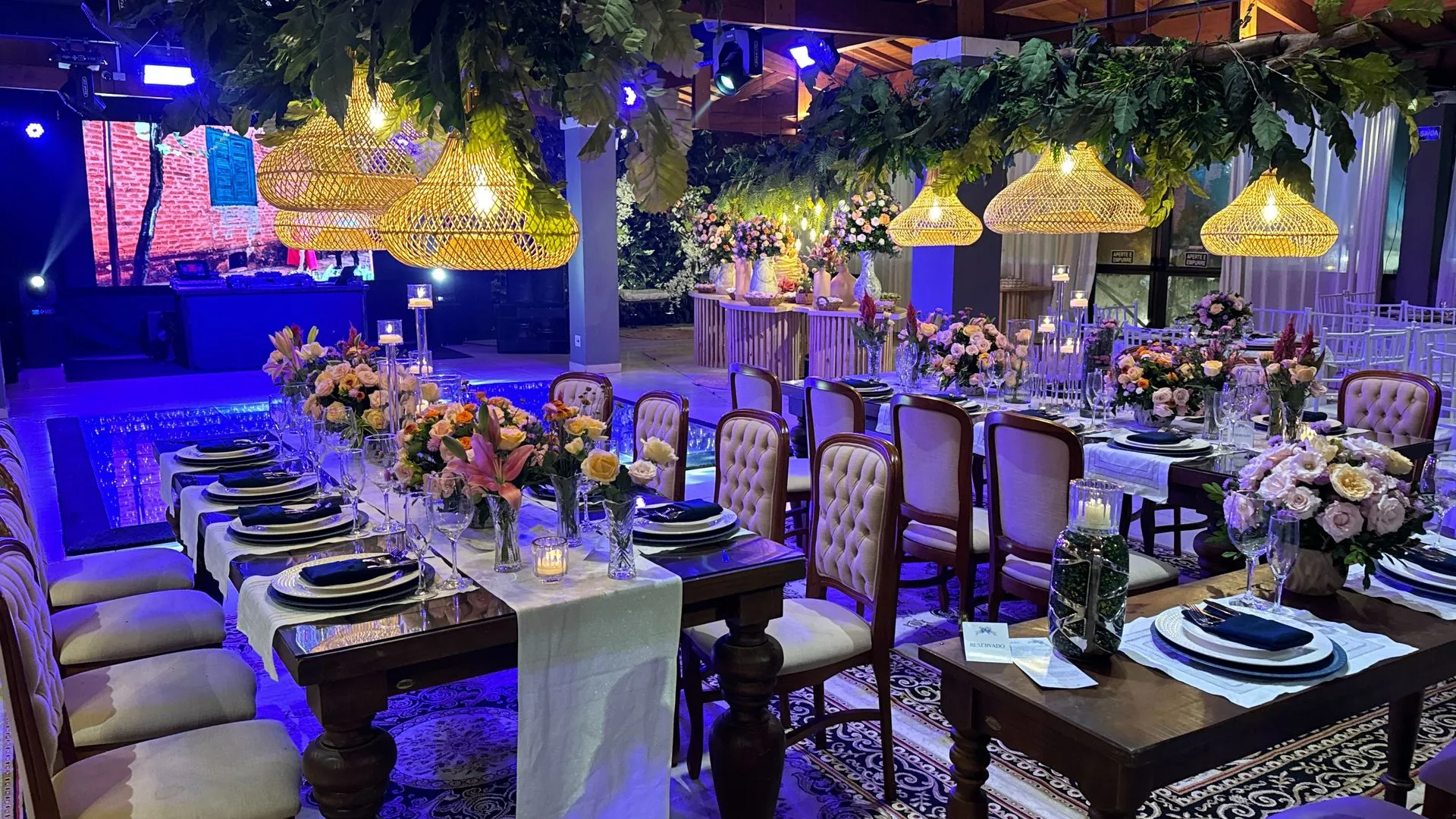 Uma grande sala com mesas e cadeiras preparadas para uma recepção de casamento.