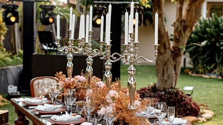 Uma longa mesa com velas e flores em um jardim.