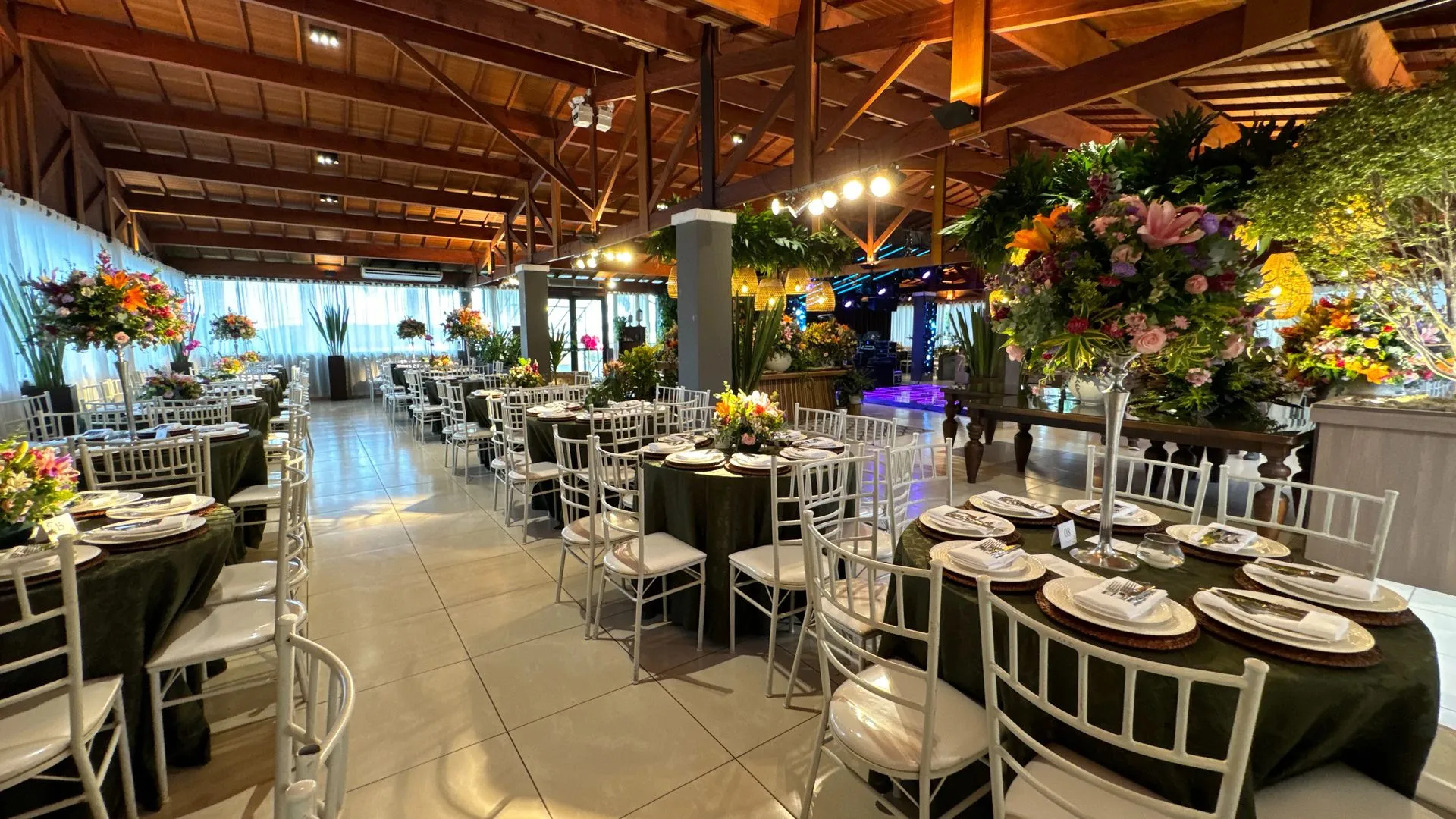 Uma grande sala com mesas e cadeiras preparadas para uma recepção de casamento.