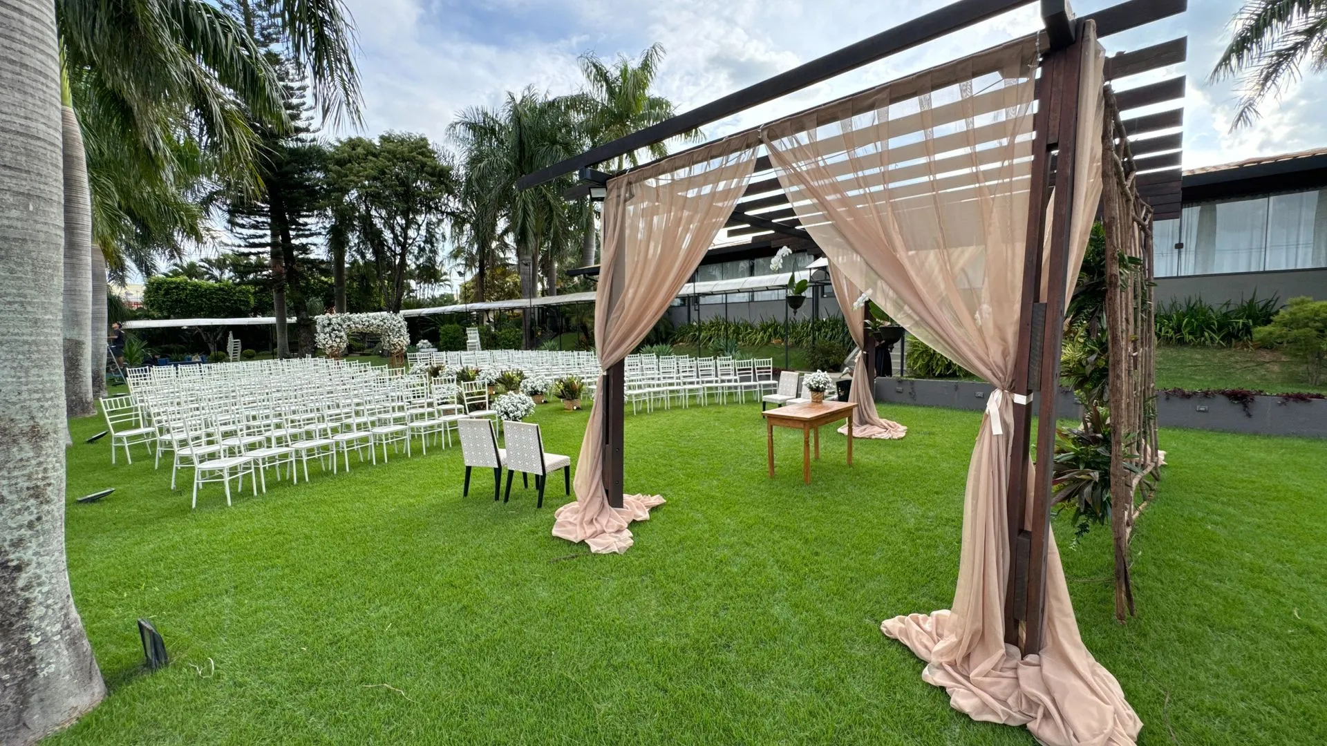 Uma cerimônia de casamento está acontecendo em um campo verdejante.