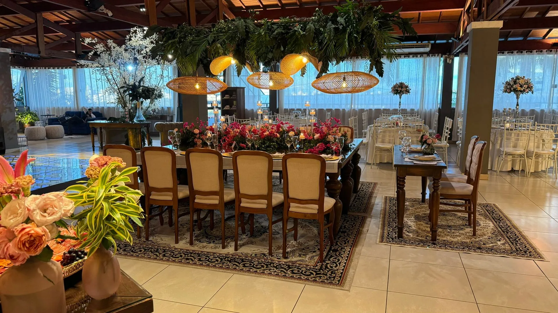 Uma grande sala com mesa e cadeiras e flores no chão.