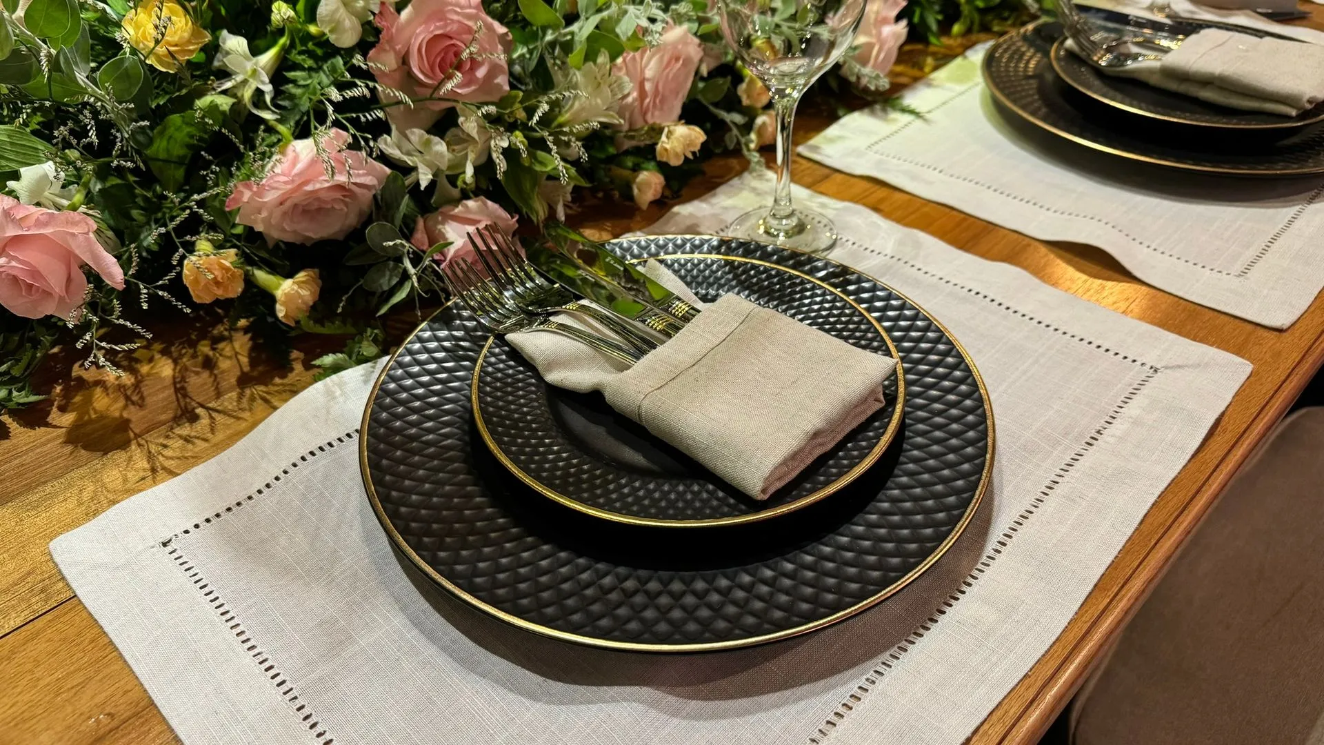 Uma mesa com pratos, guardanapos e flores.