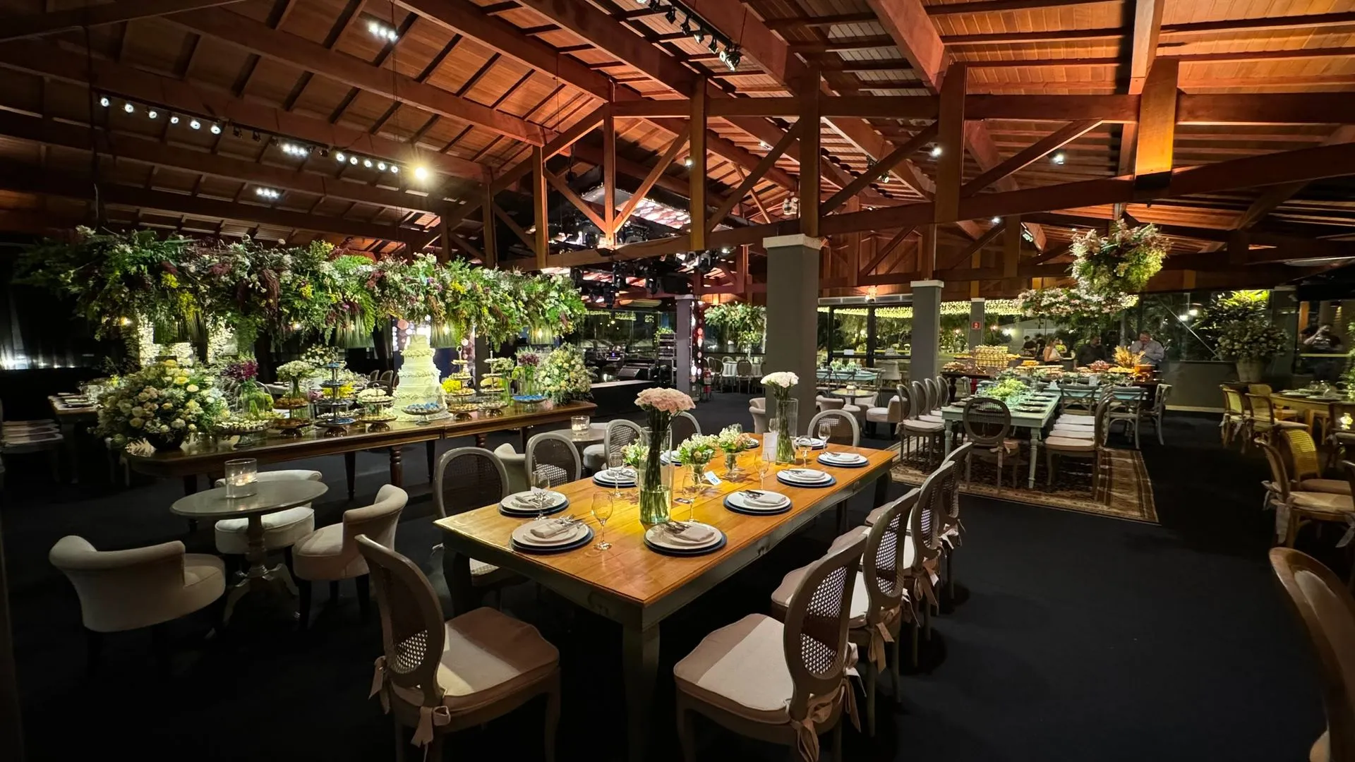 Uma grande sala com mesas e cadeiras e teto de madeira.