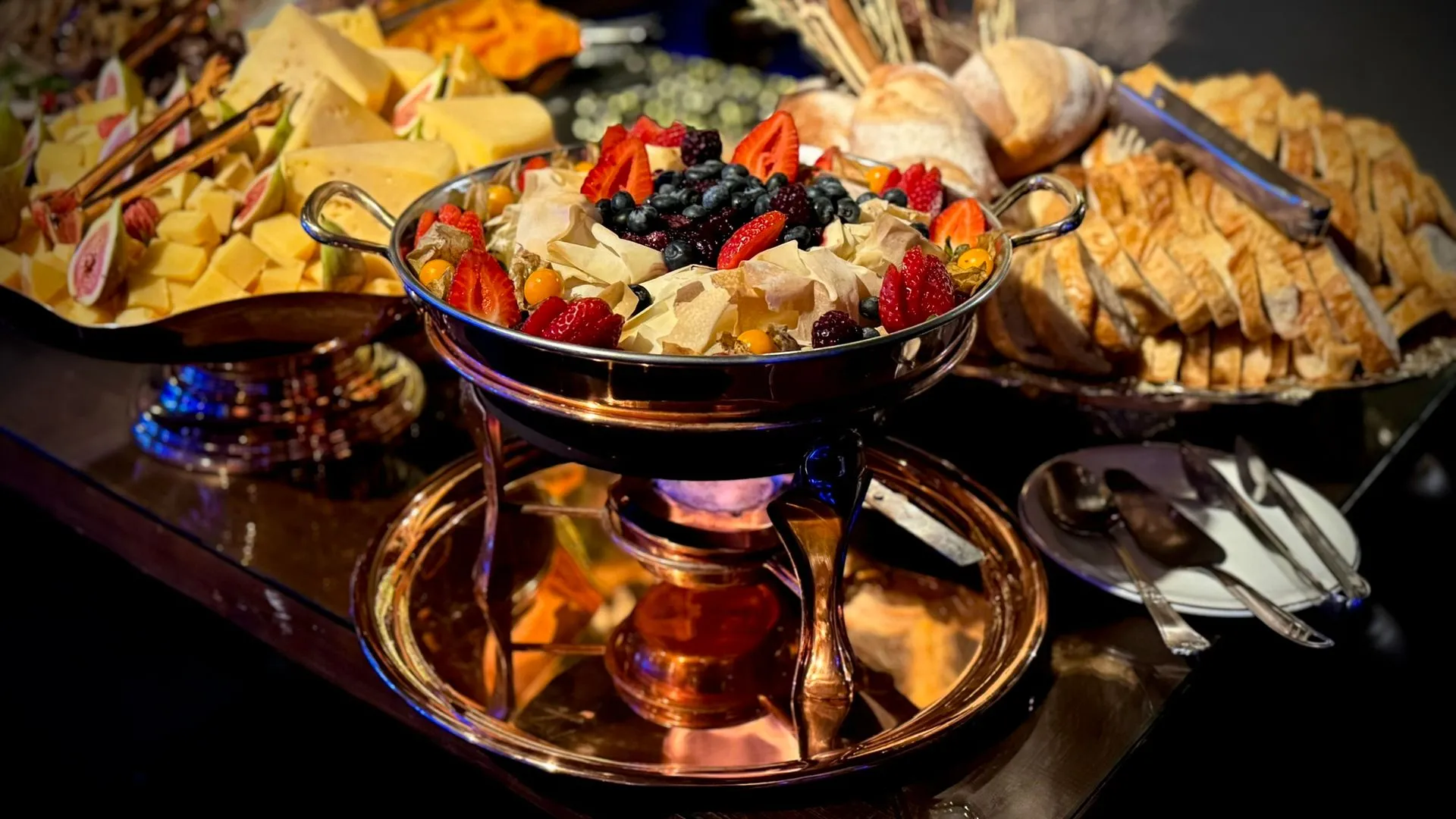 Uma mesa de bufê com uma tigela de frutas e legumes.