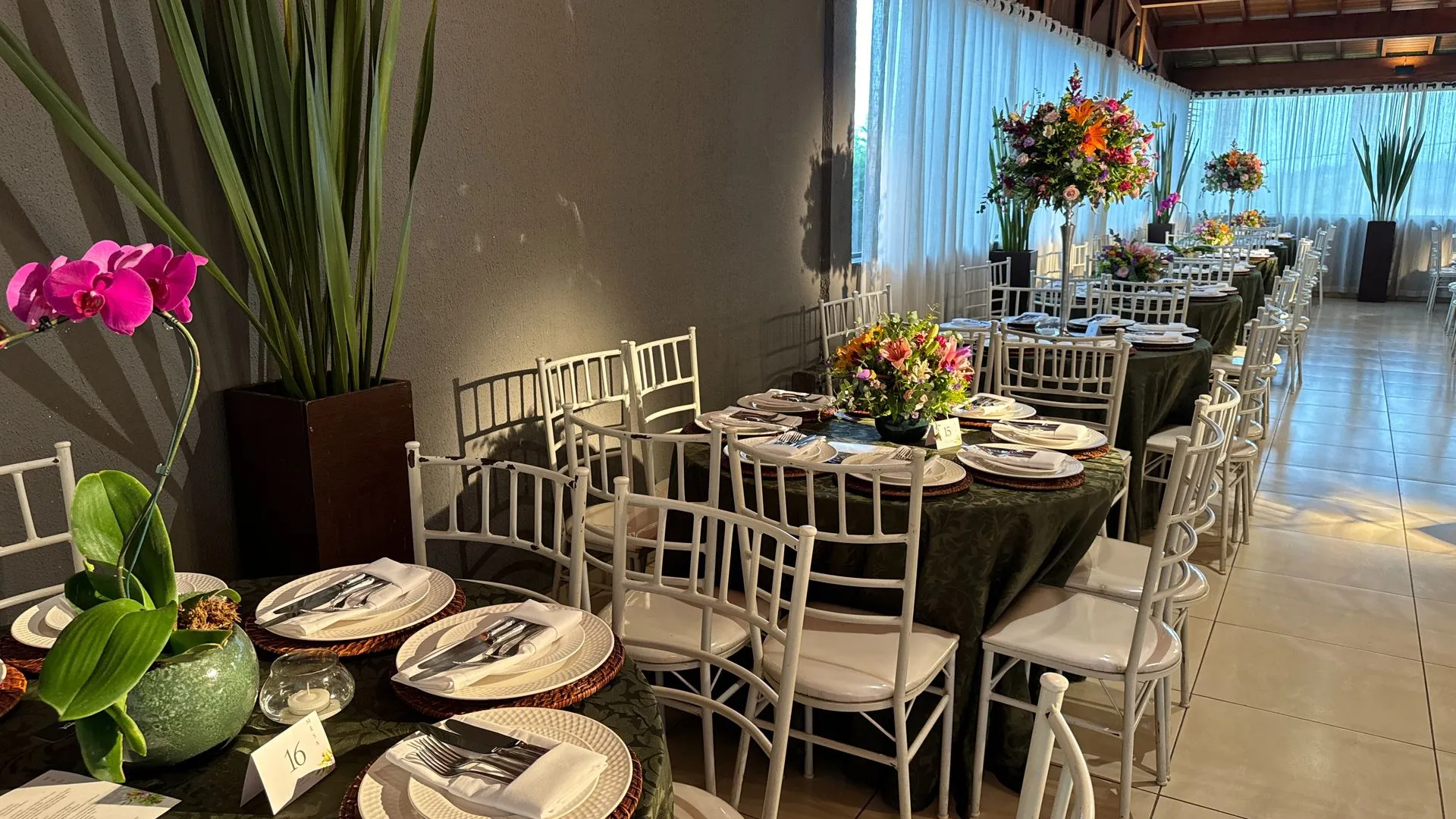 Uma grande sala com mesas e cadeiras preparadas para uma recepção de casamento.