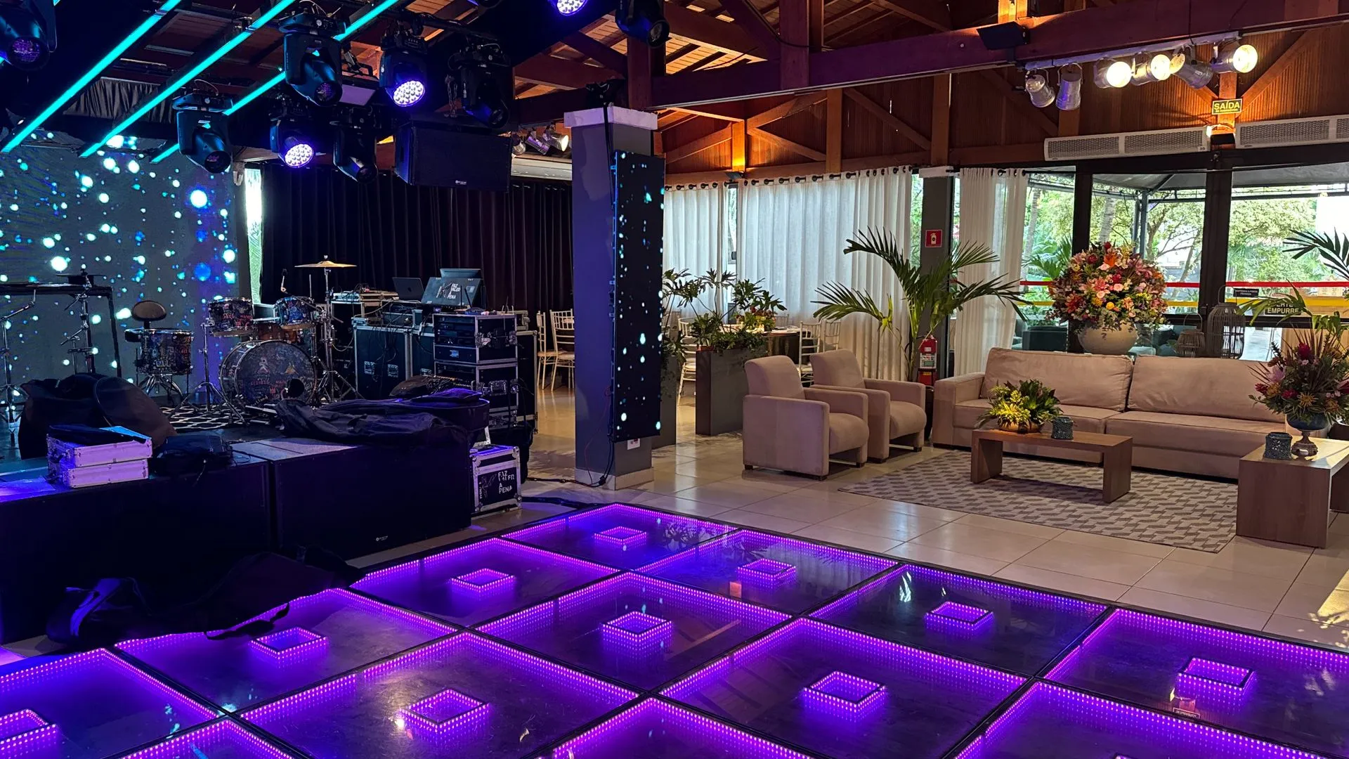 Há uma pista de dança com luzes roxas no meio da sala.