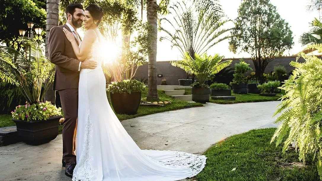 Os noivos posam para uma foto em um jardim.